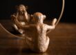Ornamental statuette in form of macaque reflecting differently in mirror on wooden table at home