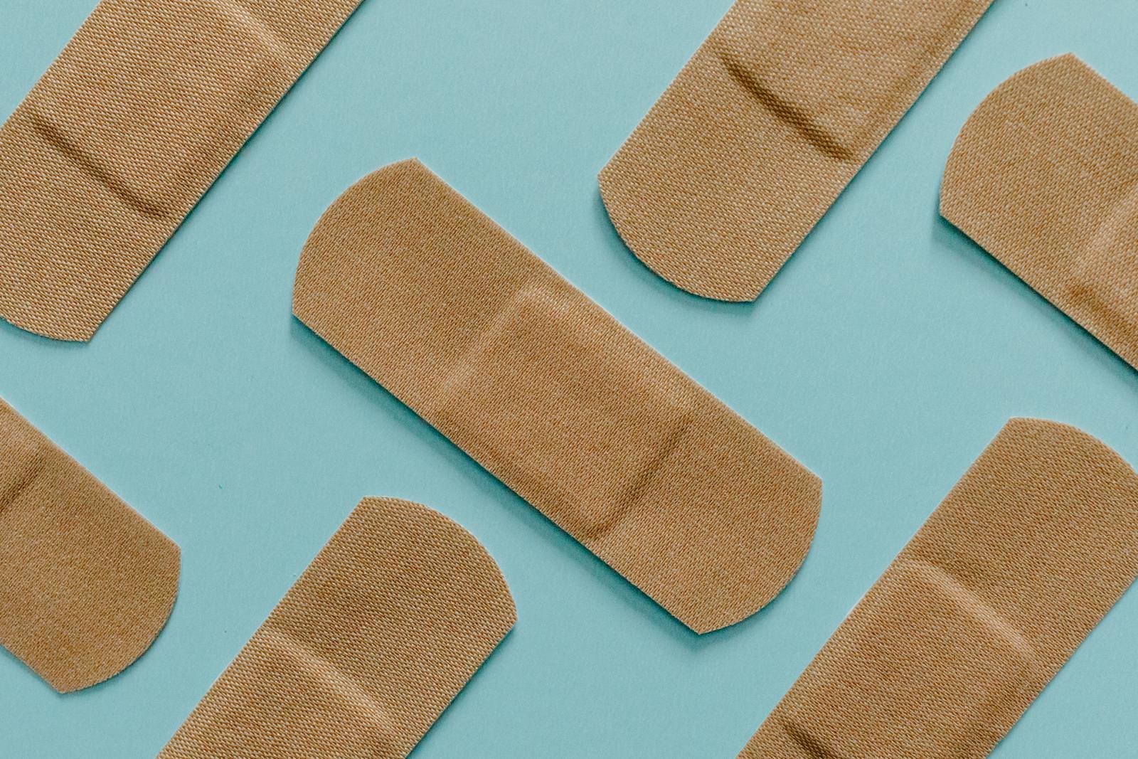A minimalist flat lay of adhesive bandages on a blue background, perfect for health and treatment themes.
