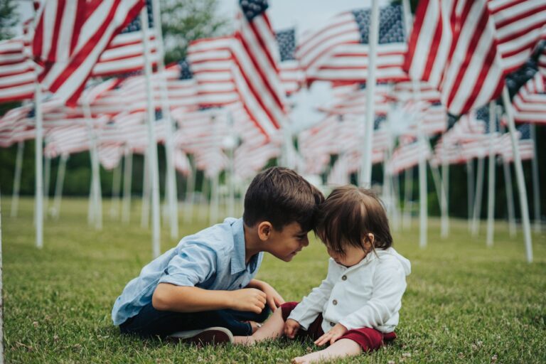boy in blue t-shirt and blue shorts sitting on green grass field during daytime