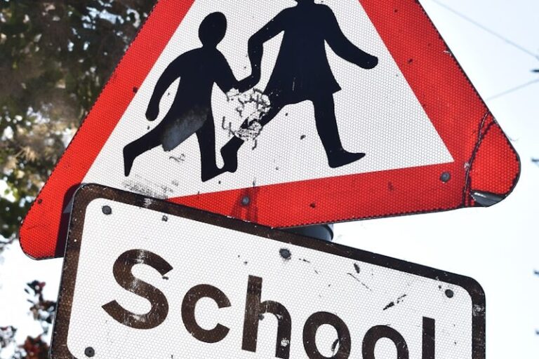 a red and white sign that says school and a black and white sign that says
