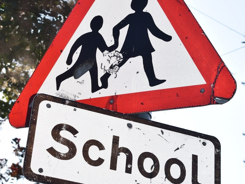 a red and white sign that says school and a black and white sign that says
