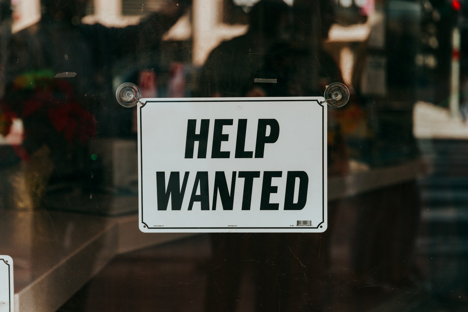 Photo by Nathan Dumlao a sign that says help wanted on a glass door